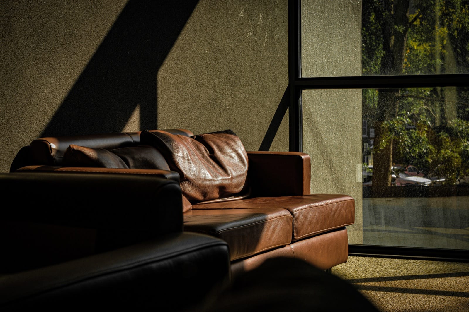 Braunes Ledersofa im warmen Licht neben einem Fenster